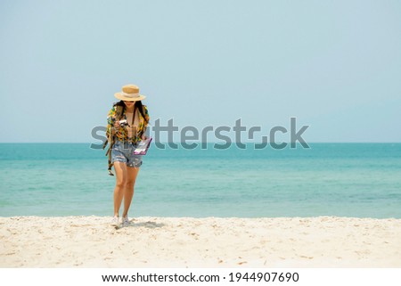 Asian woman traveler with backpack holding camera and map walking on the beach enjoy life , freedom of  feemale woman at beach , Travel holiday summer vacation healthy Concept 