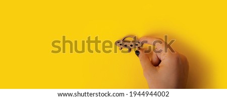 wooden symbol UFO in hand over yellow background, panoramic mock-up with space for text