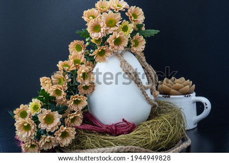 A large egg in a nest covered with flowers. Still life. Easter holiday.