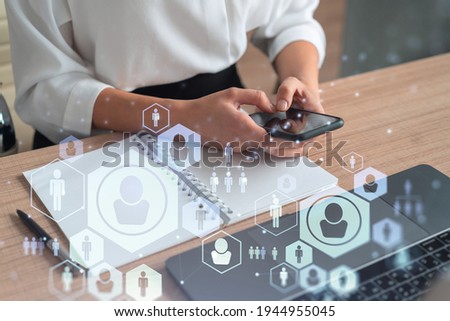 HR woman specialist in formal wear browsing social networks in the Internet in smart phone to find the best candidates to hire international team. Concept of success. Media hologram icons.