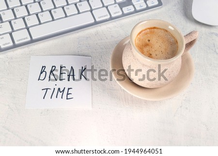 Break time. Concept time off. Words BREAK TIME in note on the working table with cup of coffee and keyboard.
