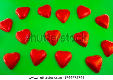 Chocolate candies shape of hearts on green background