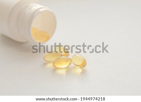 White jar and pills of fish oil on a white background