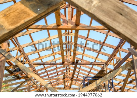 Photo of the wooden house roof and wooden roof structure on the construction site.