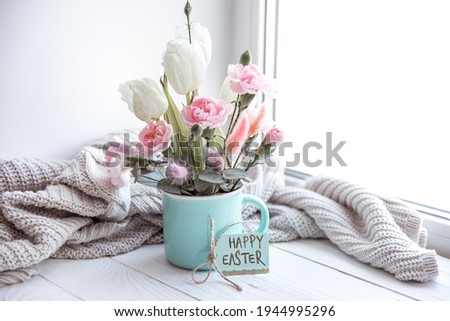 Still life with fresh flowers in a vase, a Happy Easter card and a knitted element.