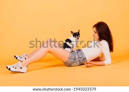 Young woman cuddling chihuahua puppy in studio, isolated