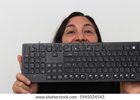 Black haired woman with keyboard raised to her face on white background