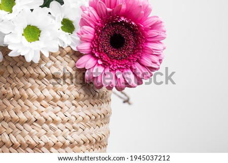 macro of a wicker basket with white flowers and a rose on a white background, horizontal photo