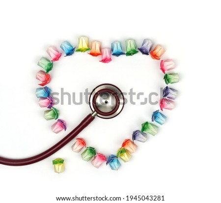 Various colored paper folded in the shape of a rabbit arranged in a heart with  a stethoscope on a white background.
