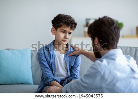 Father and sad son having heart to heart talk at home, daddy trying to solve problems, searching solution together. Parent showing care and love, calming down boy and holding hand on shoulder Royalty-Free Stock Photo #1945043575