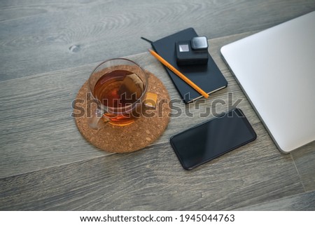 Notebook, action cam, laptop, smart phone and cup of tea on wooden desktop. Recording equipment and shooting video for vlogger and podcasters. Home working, content creators and technology concept.