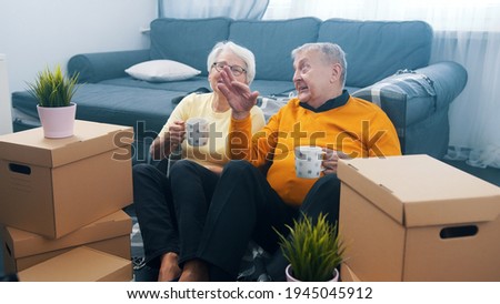 Happy retired couple relocating to new appartment. Drinking coffee surounded by cardboard boxes. buying new property. High quality photo