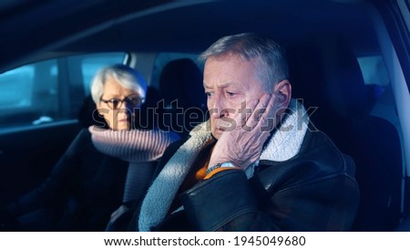 Elderly couple in the car confused with flashing police lights. Speeding ticket. Man and woman having argument in the car. High quality photo Royalty-Free Stock Photo #1945049680
