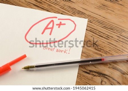 A graded school paper marked in red ink over a wood desktop. Royalty-Free Stock Photo #1945062415