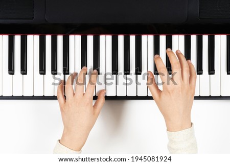 Kid hands learning to play on the piano. Top view