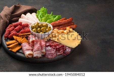 Sausage and cheese slicing on a round cutting board on a brown background. Side view with copy space. Royalty-Free Stock Photo #1945084012