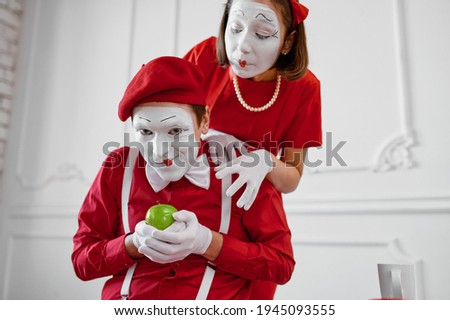 Two mime artists in red costumes, scene with apple