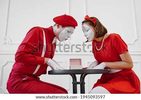 Male and female mime artists are looking on gift