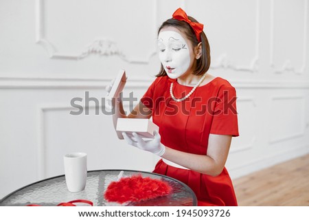 Female mime artist in red costume, scene with gift