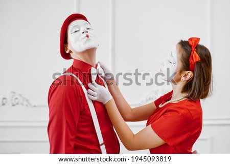 Mime artists in red costumes look at each other
