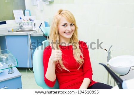 Closeup portrait happy, satisfied smiling woman, female, patient  in office, dental clinic giving thumbs up sign. Doctor visit. 