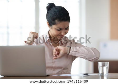 Upset anxious young Indian female employee work on laptop in office look at watch worried about deadline. Frustrated mixed race woman feel stressed worry about time management, finish job on time. Royalty-Free Stock Photo #1945116409