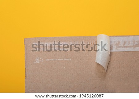 Resealable package for ecommerce products, fashion items returning. Sticky self adhesive sealing tape on corrugated cardboard box Royalty-Free Stock Photo #1945126087