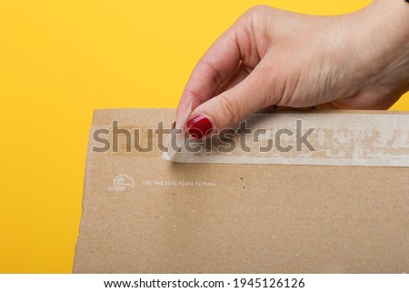 Resealing a package for ecommerce products, fashion items returning. Sticky self adhesive sealing tape on corrugated cardboard box Royalty-Free Stock Photo #1945126126