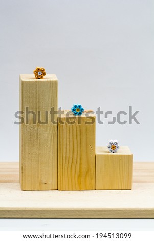 Wooden geometrical pieces with paper flowers and light grey background