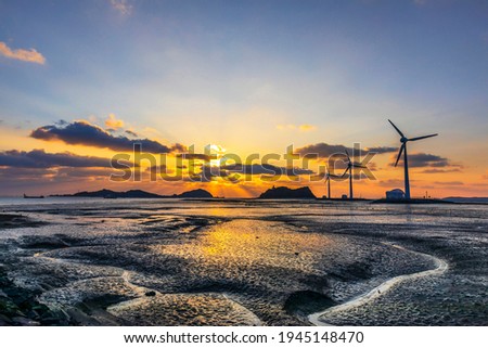 Sunset view of mud flat at Tando Port of Daebudo Island with the background of wind power generators near Ansan-si, South Korea 
 Royalty-Free Stock Photo #1945148470
