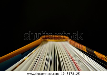 Top detail of a book spine with open sheets, with a dark background and space for text, yellow and dark blue colors, ideal for Book Day. interior picture