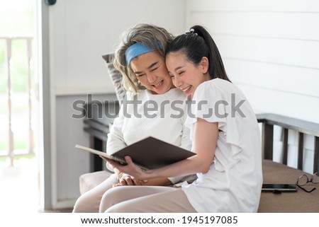 Elderly Mother and adult daughter looking photo book resting at hom