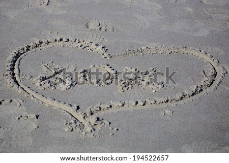 Hugs and Kisses Picture of drawing of a heart with writing inside of it in the sand.