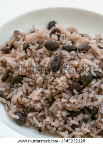 Rice with black beans served in a white bowl on a white tablecloth, widely consumed in the Dominican Republic and known as moro.