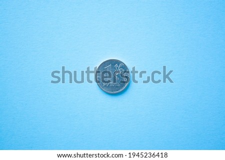 Coin one rouble on bright blue background. ruble depreciation. Rouble to dollar