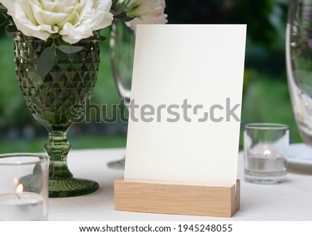 Mockup white blank space card, for greeting, table number, wedding invitation template on wedding table setting background. with clipping path Royalty-Free Stock Photo #1945248055