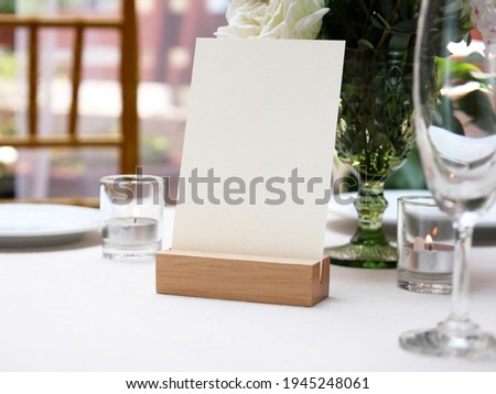 Mockup white blank space card, for greeting, table number, wedding invitation template on wedding table setting background. with clipping path Royalty-Free Stock Photo #1945248061