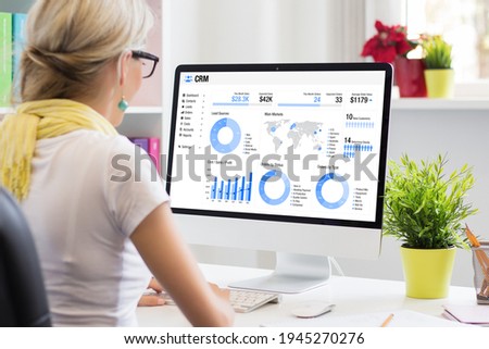 Woman working in office with a computer with different graphs, charts and infographics on screen