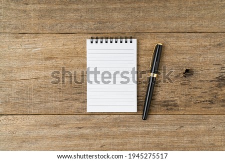Notebook and pen on shabby wooden board background. Copy space.