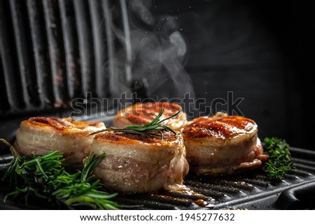 Cooking beef steak on grill. beef tenderloin steaks wrapped in bacon. filet Mignon. ground pepper in a freeze motion,