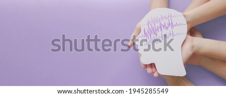 Adult and child hands holding encephalography brain paper cutout, autism, Epilepsy awareness, seizure disorder, stroke, alzheimer, mental health concept Royalty-Free Stock Photo #1945285549