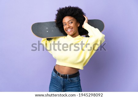 Young African American woman isolated on purple background with a skate and looking up