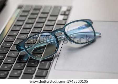 Eyeglasses on laptop on wooden table, close up