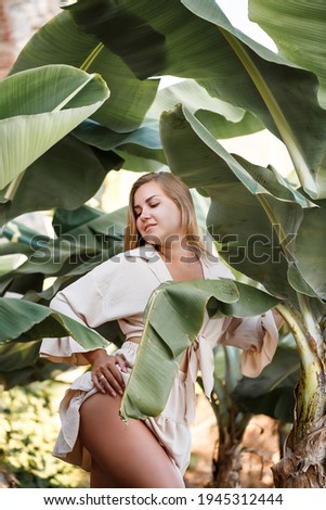 Beautiful woman in the jungle. A resort or hotel with tropical trees and plants. Woman with near banana leaf. Girl on vacation in the rainforest