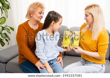 little girl mother and grandmother hold photo canvas in the interior