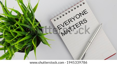 Keyword everyone matters - business concept text on white notebook and pen, green flowers