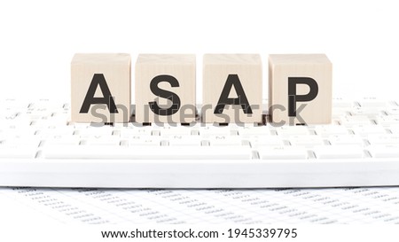 ASAP -word wooden block on the keyboard background witn chart