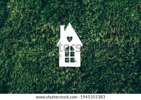 Zero waste, organic, sustainable lifestyle. Trendy eco home in nature. Eco house concept. Top view. White house model on green grass, forest moss background. Top view. Copy space. Eco friendly house.
