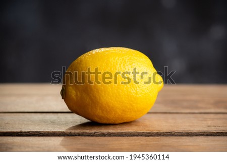 Ripe and bright lemon on the dark rustic background. Selective focus. Shallow depth of field.