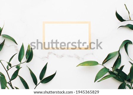 Blank white and gold card, green leaves on white background as botanical frame flatlay, wedding invitation and branding, flat lay design concept